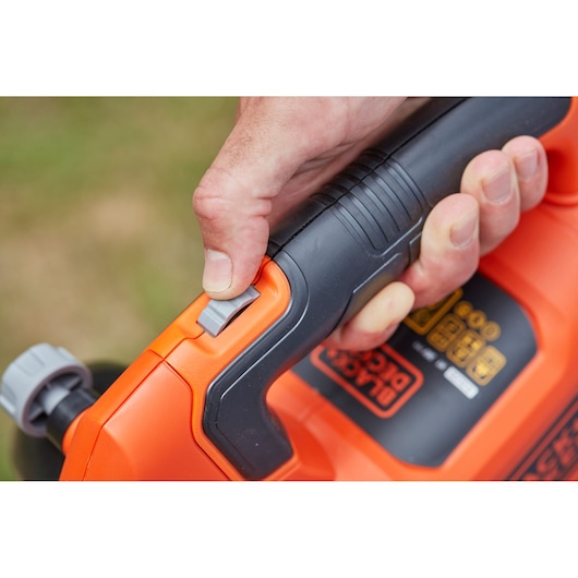 Close-up of hand pressing trigger on BLACKDECKER BCBLV3625L1 orange and black cordless blower handle.