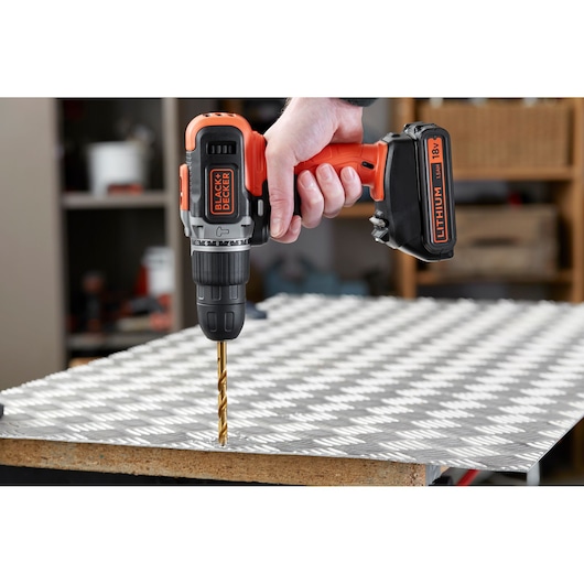 BLACK+DECKER cordless drill BCD003C2K in use, drilling into metal sheet, side view.