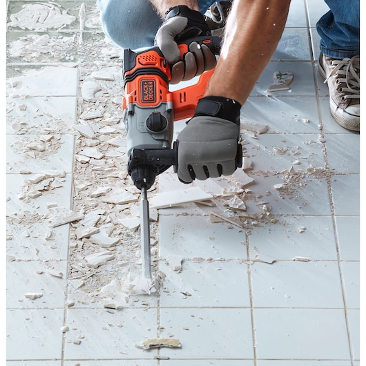 BLACKDECKER BCD900E2K rotary hammer in use breaking tiles on floor, close-up photography.