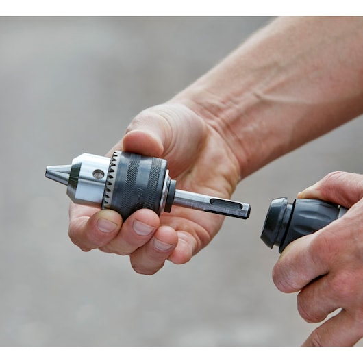 BLACKDECKER BCD900E2K hammer drill chuck attachment being installed, close-up on hands holding components.