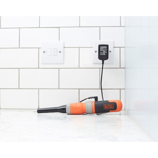 BLACK+DECKER BCF603C cordless screwdriver charging on marble countertop with white tile backsplash.