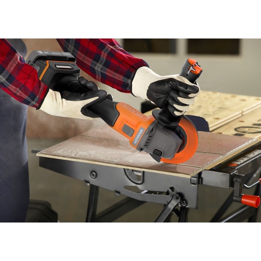BLACKDECKER BCG6L8N cordless angle grinder in use, cutting tile on a workbench, close-up side view.