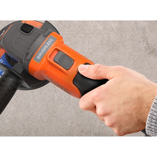 Close-up photo of a hand operating BLACKDECKER BCG6L8N cordless angle grinder with visible brushless motor label.