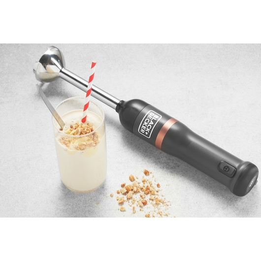 Photo of BLACK+DECKER BCKM1011KGF hand blender with black handle and silver shaft next to a glass of dessert on countertop.