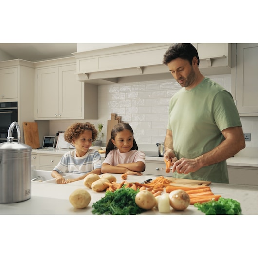 BLACKDECKER BCKM1011KGF stainless steel compost bin on kitchen counter with potatoes, carrots, and greens in foreground.