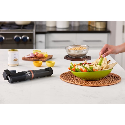 BLACKDECKER BCKM1011KGF cordless kitchen multitool on countertop with green bowl of vegetables and pita.