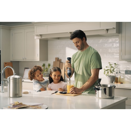 BLACKDECKER BCKM1011KGF hand blender mixing orange liquid in a kitchen scene with people.