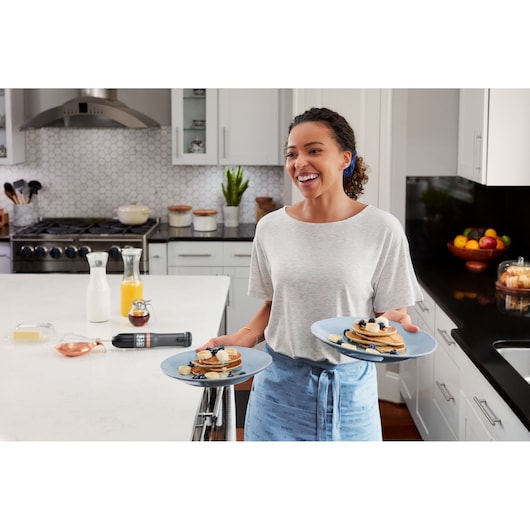 BLACKDECKER BCKM1011KGF cordless hand mixer on a kitchen counter with milk, juice, and breakfast foods.