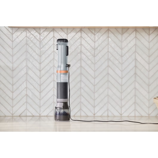 BLACK+DECKER BCKM1012KG stick vacuum cleaner standing upright on a kitchen counter, side view.