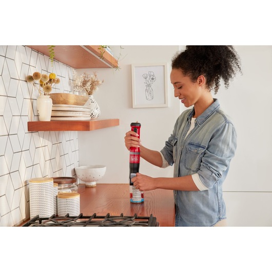 Photo of BLACK+DECKER BCKM1012KR cordless kitchen mixer in red used by person on kitchen counter.