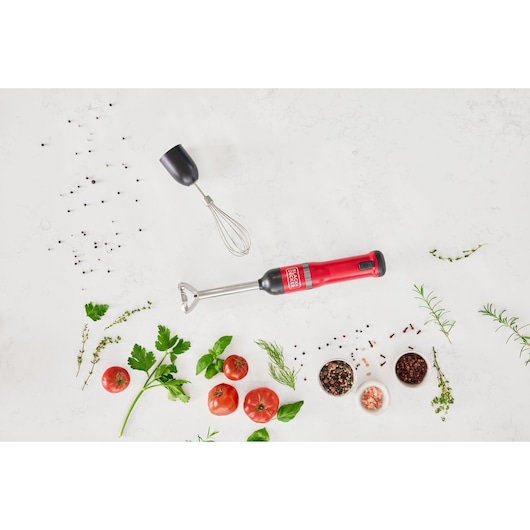 Photo of BLACKDECKER BCKM1012KR hand blender with whisk attachment, red handle, surrounded by fresh herbs and tomatoes.
