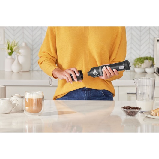 Photo of BLACKDECKER BCKM1016KSB milk frother held by person in kitchen, coffee and ingredients nearby.