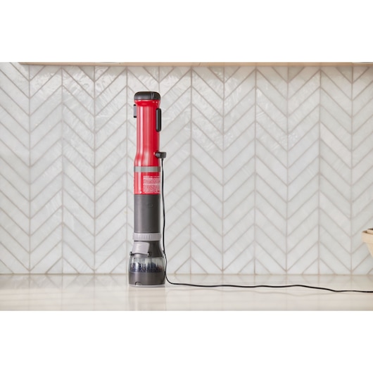 BLACKDECKER BCKM1016KSR red and black cordless stick vacuum on white countertop, front angle.