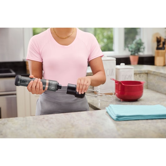 Photo of BLACK+DECKER BCKM101HM hand mixer being assembled in a kitchen, with a red bowl and blue towel nearby.