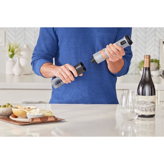 Photo of a person filling a BLACKDECKER BCKM101WNFF electric spice grinder in a kitchen setting.