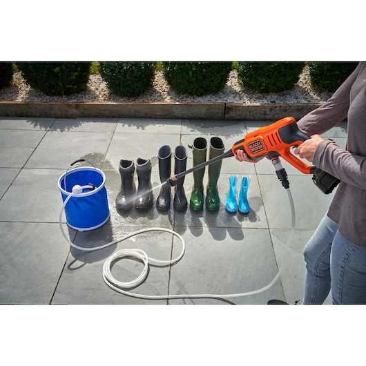 BLACKDECKER BCPC18B portable pressure washer cleaning boots outdoors, side angle.