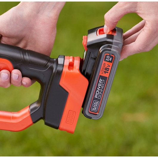 Close-up of BLACKDECKER BCPC18D1 18V lithium battery being attached to a cordless tool outdoors.
