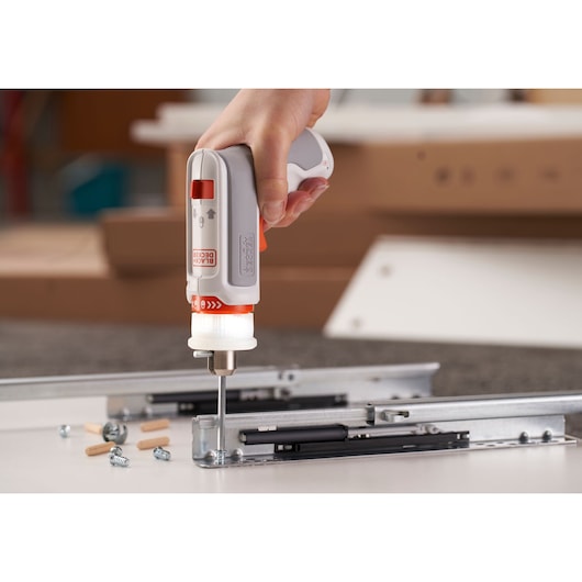BLACKDECKER BCRTA01 gray and orange electric screwdriver assembling drawer slide on a tabletop.