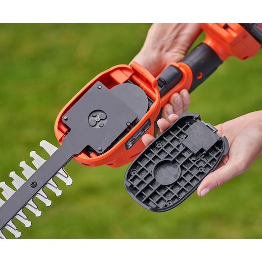 BLACKDECKER BCSS18B hedge trimmer shown with back cover removed, revealing internal mechanism, outdoor setting.