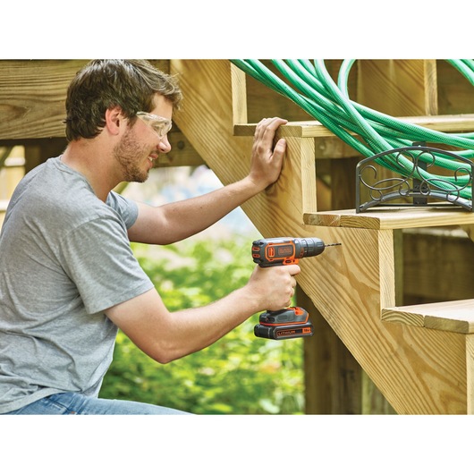 Photo of BLACKDECKER BDCDC18KB cordless drill used on wooden stairs outdoors.