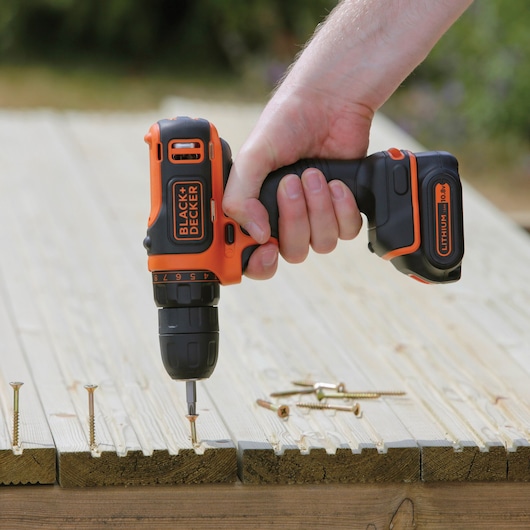 BLACK+DECKER BDCDD12K cordless drill driver in use on wood, close-up of the tool and screws.