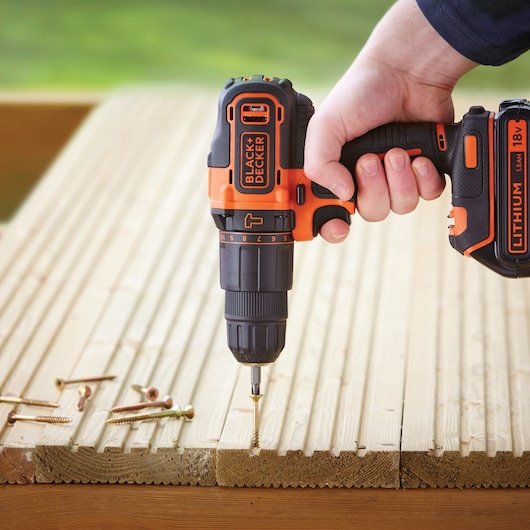 BLACK+DECKER BDCHD18K cordless drill driving screw into wood, close-up outdoor setting.