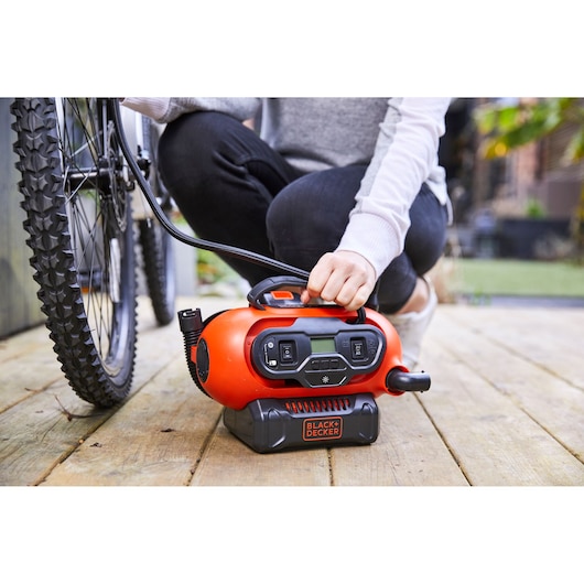 BLACKDECKER BDCINF18N portable air inflator used to inflate a bicycle tire outdoors.