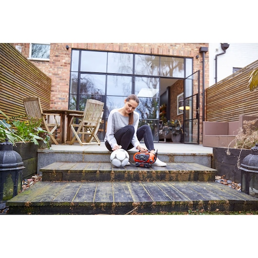 BLACKDECKER BDCINF18N portable inflator next to soccer ball on outdoor steps, residential setting.
