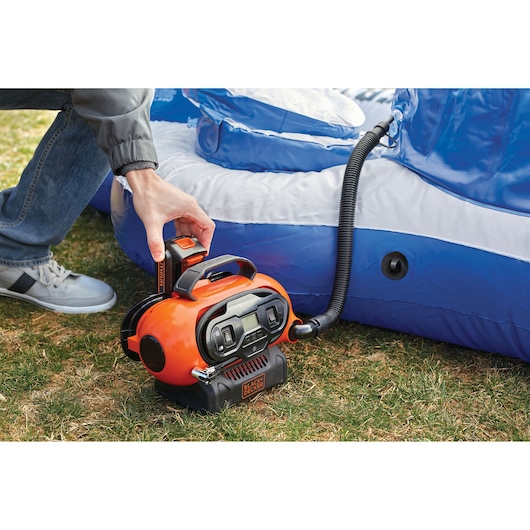 BLACKDECKER BDCINF18N portable inflator in use inflating a blue and white pool outdoors.