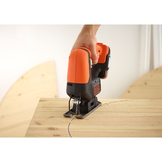 BLACKDECKER BDCJS12N jigsaw in use, cutting curved line into wooden board, close-up photography.