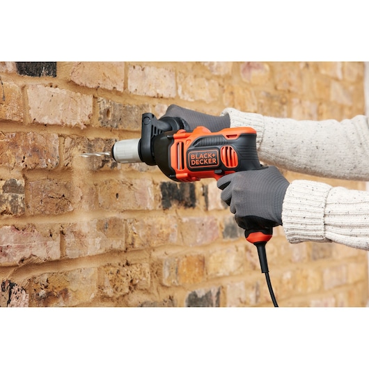 BLACKDECKER BEH850K corded hammer drill in use drilling into brick wall, close-up view.