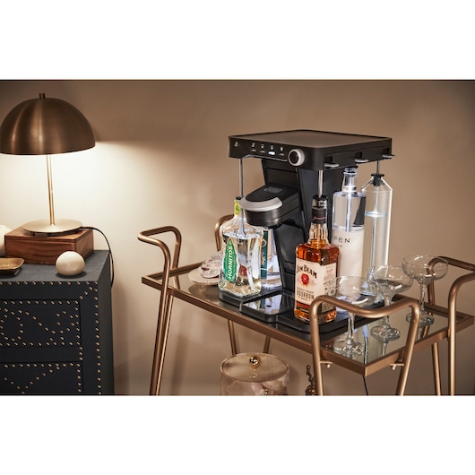 BLACKDECKER BEHB101 coffee maker on bar cart with various liquor bottles and glasses, indoor setting.