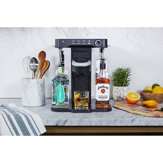 BLACKDECKER BEHB101 countertop drink mixer with two liquor bottles and a cocktail glass, kitchen background.