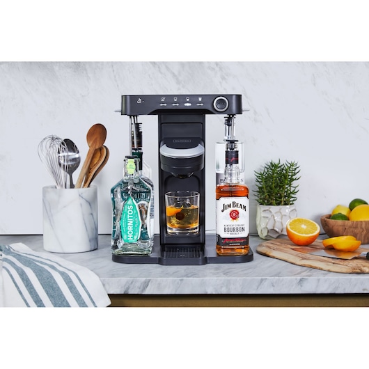 BLACKDECKER BEHB101 drink maker front angle with liquor bottles on each side, glass with cocktail, kitchen setting.