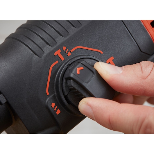 Close-up photo of a hand adjusting the BLACKDECKER BEHS01 rotary hammer mode selector switch, black and red detail.