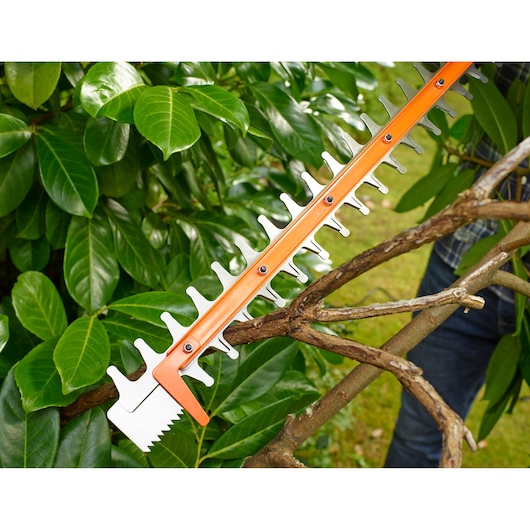 BLACKDECKER BEHTS401 hedge trimmer blade cutting a tree branch outdoors, close-up photography.