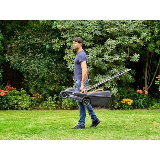 Photo of BLACKDECKER BEMW351 lawn mower being carried on grass in a garden.
