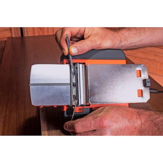 BLACKDECKER BEW712 power tool with metal base, shown in close-up during adjustment on wooden surface.