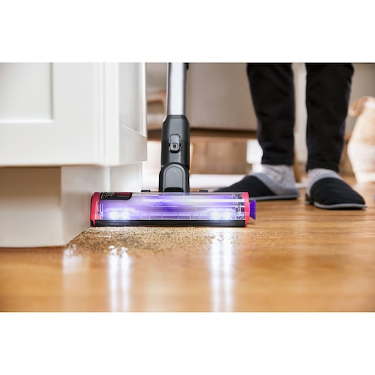 BLACKDECKER BHFEA640WP cordless stick vacuum with LED lights cleaning hardwood floor near cabinet, front angle.
