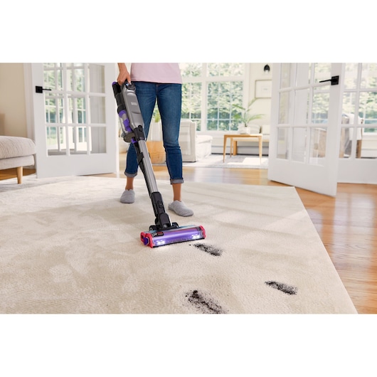 BLACKDECKER BHFEA640WP cordless stick vacuum cleaning dirt on a light carpet in a bright living room.