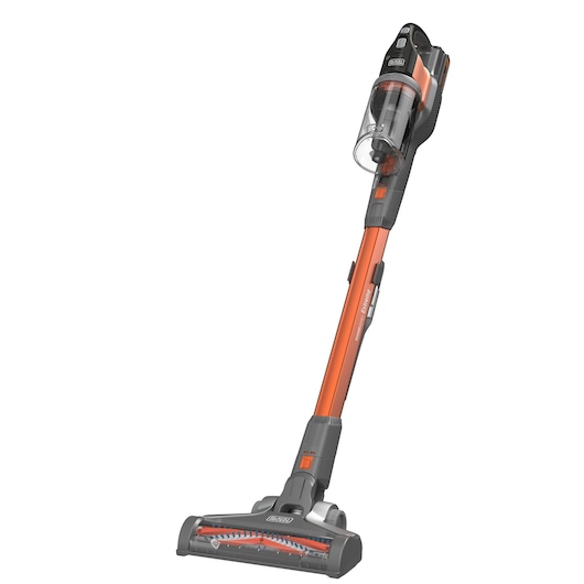 A BLACK+DECKER cordless stick vacuum cleaner with an orange and grey design, featuring a transparent dust collection canister and motorized brush head.