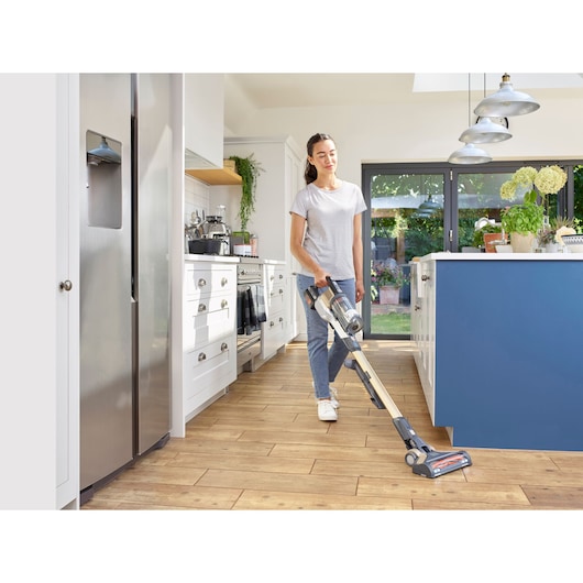 BLACKDECKER BHFEV36B2DW cordless stick vacuum cleaner in use on kitchen floor.