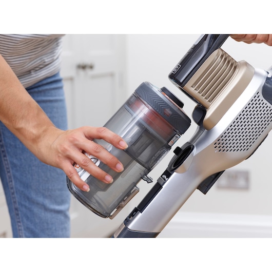 BLACKDECKER BHFEV36B2DW cordless vacuum with person removing dust container indoors.