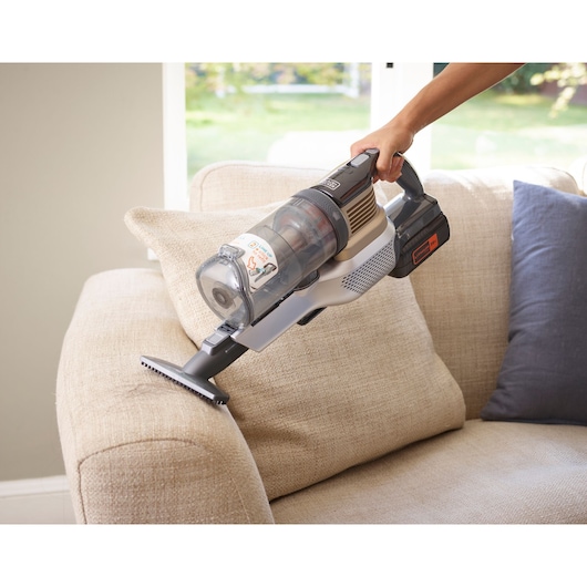 BLACKDECKER BHFEV36B2DW cordless handheld vacuum used to clean a beige sofa cushion indoors.