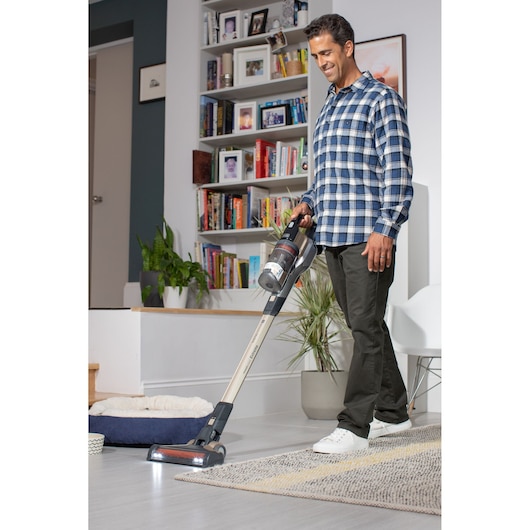 BLACKDECKER BHFEV36B2DW cordless vacuum cleaner in use on living room rug, shown from side angle.