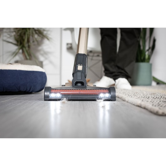 BLACKDECKER BHFEV36B2DW vacuum cleaner head with LED lights cleaning hardwood floor near rug.