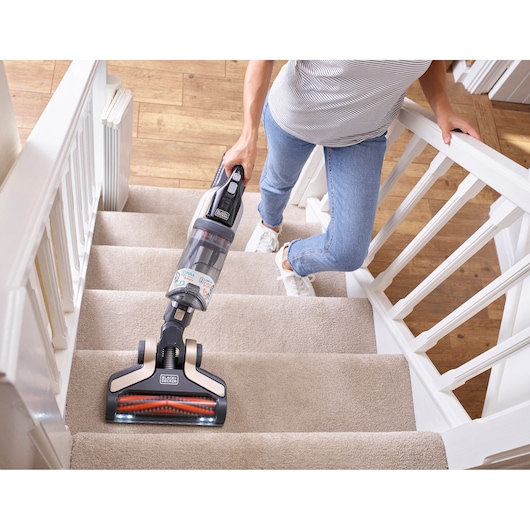BLACKDECKER BHFEV36B2D cordless vacuum cleaner cleaning carpeted stairs, handheld use shown.