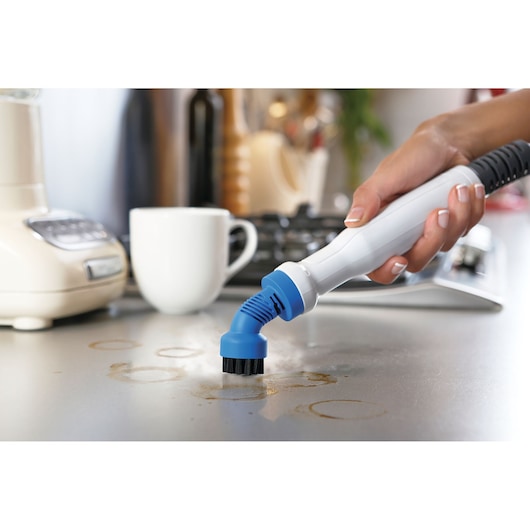 BLACKDECKER BHSM1615DSG handheld steam cleaner with blue brush head cleaning a kitchen countertop.