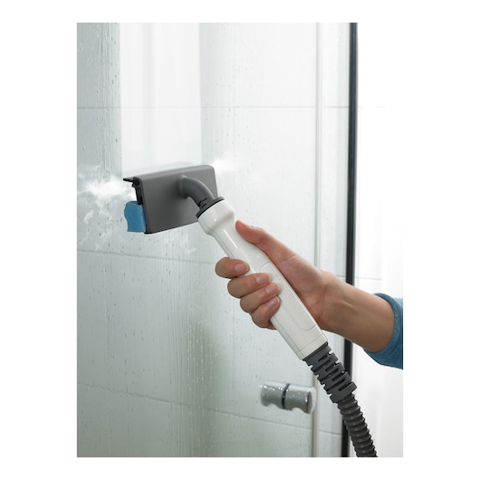 BLACKDECKER BHSM1615DSM steam cleaner cleaning a glass shower door, close-up of hand holding handle.