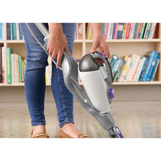 BLACK+DECKER BHSM1615DSM steam cleaner with detachable handheld unit in use on floor, bookshelf in background.